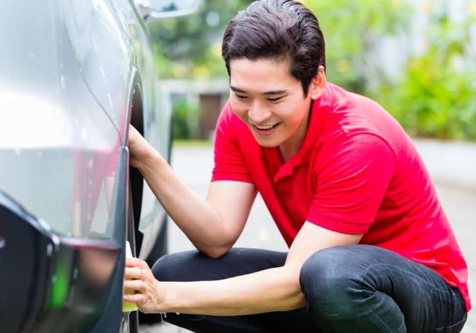 Asian man cleaning car rims with sponge