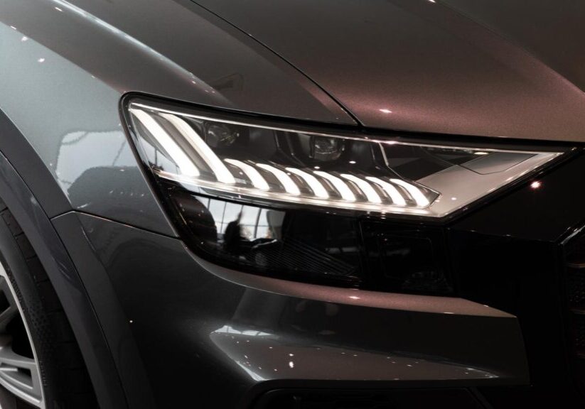 headlight of a gray modern car close-up in a car dealership.